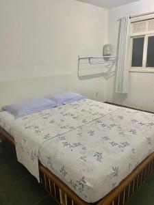 a bedroom with a bed with a blue and white comforter at CASA EM GUARAPARI in Guarapari