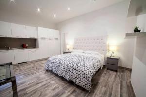 a white bedroom with a bed and a kitchen at APPARTAMENTI MUSEO 3 in Verona