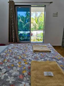un letto in una stanza con una finestra e due asciugamani sopra di Oxygen Resort, Akshi a Alibag