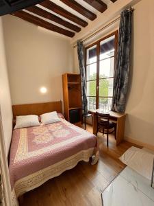 a bedroom with a bed and a desk and a window at Hôtel Des Fontaines in Paris
