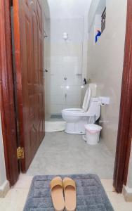 une salle de bains avec des toilettes et une paire de chaussures dans l'établissement Jay Homes - Rehema Apartments, à Naivasha 15 autres photos