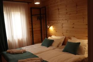 a large bed in a bedroom with a wooden wall at Cottage Deera in Mestia