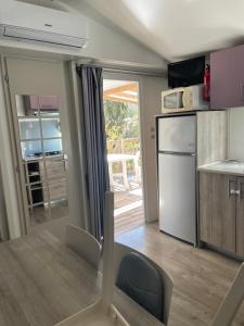 una cucina con tavolo, sedie e frigorifero di Mobil-home 3 chambres, Plage & piscine, camping 4 étoiles a Torreilles