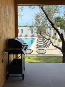 a grill on a cart in front of a pool at Mobile Home Aura, Village Twins in Pakoštane