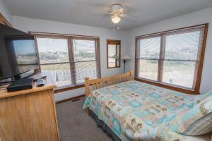 a bedroom with a bed and a flat screen tv at The Sandy Edge - OBX in Kitty Hawk +22 photos