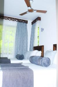 a bedroom with two beds with blue pillows and a ceiling fan at Lihanda Villa in Kilifi +42 photos