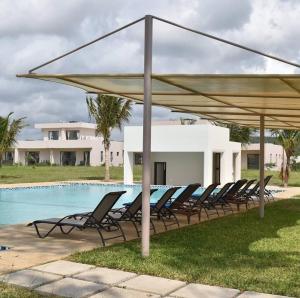 a group of chairs under a canopy next to a swimming pool at Lihanda Villa in Kilifi