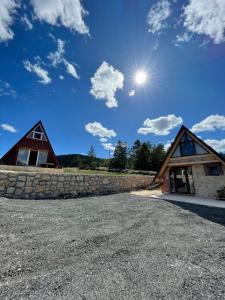 a house with a stone wall and the sun in the sky at Vila Vrela in Žabljak