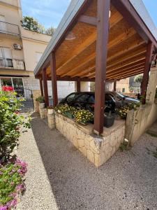 ein Auto, das unter einem Pavillon mit Blumen und Pflanzen parkt in der Unterkunft Apartment Batinica in Šibenik
