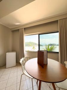 a dining room with a table and a large window at Ilha Porchat Hotel in São Vicente