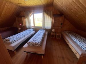 three beds in a wooden room with a window at Päikseranna Puhkemaja in Rõssa