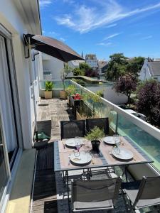 a table and chairs on a balcony with an umbrella at Appartement et terrasse Port du Pouliguen in Le Pouliguen