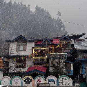 a group of buildings with snow falling on them at The Locals Manali in Manāli