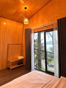 a bedroom with a bed and a large window at Đảo Ngọc Bungalow in Vĩnh Phúc