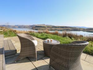 een patio met 3 stoelen, een tafel en water bij Scarba in Oban