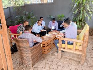 Eine Gruppe von Männern sitzt um einen Tisch und isst. in der Unterkunft Noaz Hotel in Kampala
