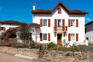a white house with a balcony on a street at Pays Basque Gite Munhoa in Anhaux