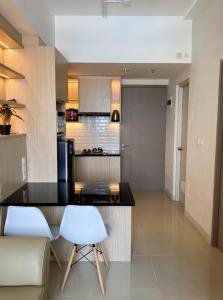 a kitchen with a counter and two white chairs at Vasanta Innopark 1BR with Sky View by Damaresa in Jarakasta +8 photos