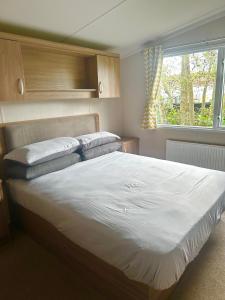 ein Schlafzimmer mit einem großen Bett mit Kissen und einem Fenster in der Unterkunft Burano Nook - Tattershall Lakes in Tattershall