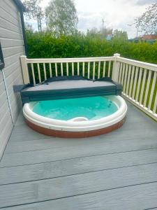 ein Whirlpool auf einer Terrasse mit einem Bett darauf in der Unterkunft Burano Nook - Tattershall Lakes in Tattershall