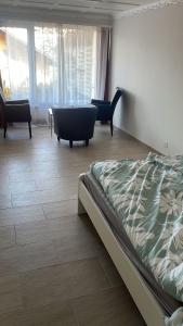 a bedroom with a bed and two chairs and windows at Dream Vacation for 4 Geusts easy to arrive in Spiez +10 photos
