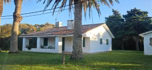 ein weißes Haus mit Palmen im Hof in der Unterkunft Casa de playa, rodeada de monte, campo y mar in La Coronilla