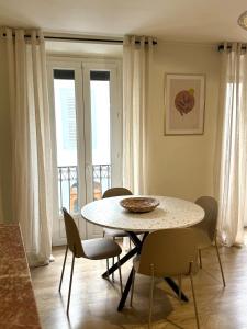 une salle à manger avec une table, des chaises et des fenêtres dans l'établissement Le cocon coloré - Appartement centre ville, à Lourdes 6 autres photos