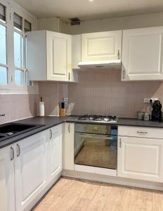 une cuisine avec des armoires blanches et un four à plaques de cuisson dans l'établissement Le cocon coloré - Appartement centre ville, à Lourdes