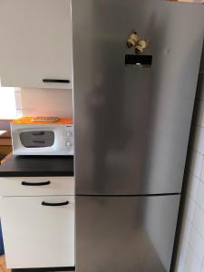 a stainless steel refrigerator in a kitchen with a microwave at Hiša Belin in Podbela +6 photos