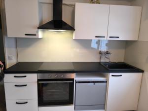 a kitchen with white cabinets and a stove top oven at Hiša Belin in Podbela