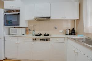 a kitchen with white cabinets and a stove top oven at Rentalsbcn Volantí in Blanes