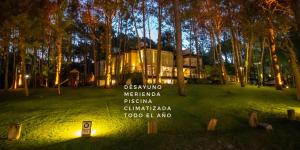 a building in a park with a sign in the grass at Sonidos Del Bosque in Mar de las Pampas