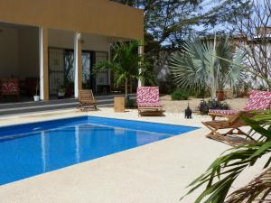 a swimming pool with two chairs and a house at villa arborée ngaparou in Ngaparou