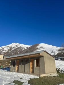 a house with snow covered mountains in the background at Mountain house in Ushguli