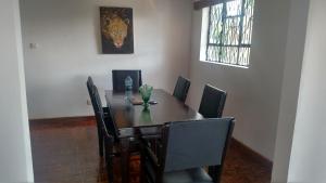 a dining room table with black chairs and a table and a picture at Eden Hill Villas - Njiro, Arusha in Nkunjila