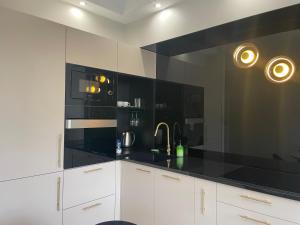 a kitchen with white cabinets and a black counter top at Najlepsza lokalizacja w Ełku!! Piękny, prestiżowy apartament z dziedzińcem !! in Ełk +8 photos