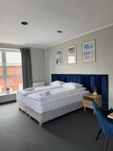 a bedroom with a large bed with a blue headboard at VistaMare in Władysławowo
