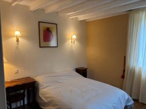 a bedroom with a white bed and a table and lights at Gite du Moulin Vieux in Vigoulant