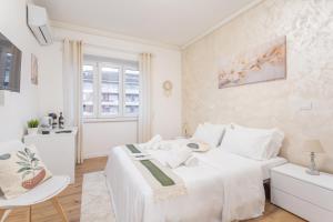 a white bedroom with a large bed and a chair at Pampas Roma in Rome