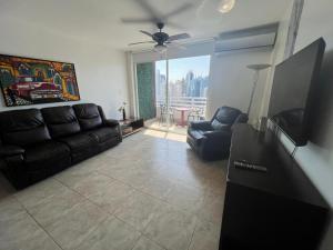 a living room with a black leather couch and chairs at Acogedor apartamento en El Cangrejo in Panama City