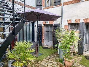 a patio with an umbrella in front of a building at Appartement T2 sur cour nantaise in Rezé