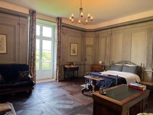 Un dormitorio con una cama, una silla y una mesa. en Château de Mauhic - 15th century, en Loubédat