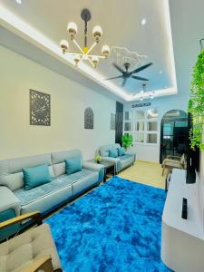 ein Wohnzimmer mit einem Sofa und einem blauen Teppich in der Unterkunft Homestay Deedora 87 in Seri Manjung