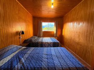 a small room with two beds and a window at Hostal Piedra Santa in Malalcahuello