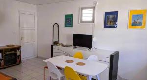 a dining room with a table and a tv at Oxygène, Havre de paix in Les Anses-dʼArlets