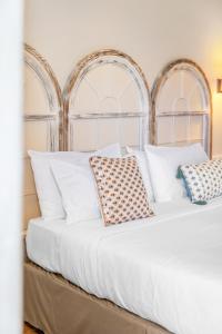 a bed with white pillows in a bedroom at Hôtel La Villa Sainte Valérie Adults Only in Juan-les-Pins