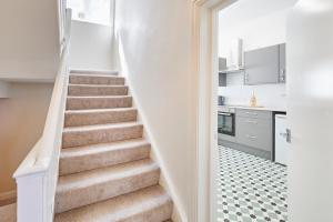 a staircase in a home with white walls and a kitchen at Painters Modern Apartment Central Location in Scarborough