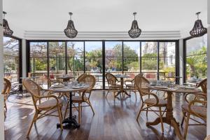 a dining room with tables and chairs and large windows at Hôtel La Villa Sainte Valérie Adults Only in Juan-les-Pins