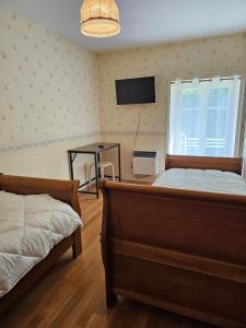 a bedroom with two beds and a television on the wall at Chambre d'hote les frérots in Lurcy-le-Bourg