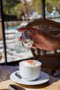 a person pouring coffee into a cup on a table at Hôtel La Villa Sainte Valérie Adults Only in Juan-les-Pins